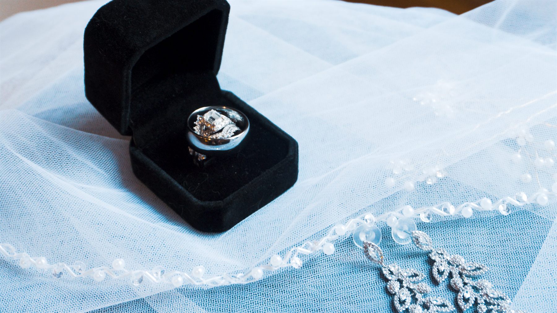 Wedding rings displayed in a black ring box on bridal fabric